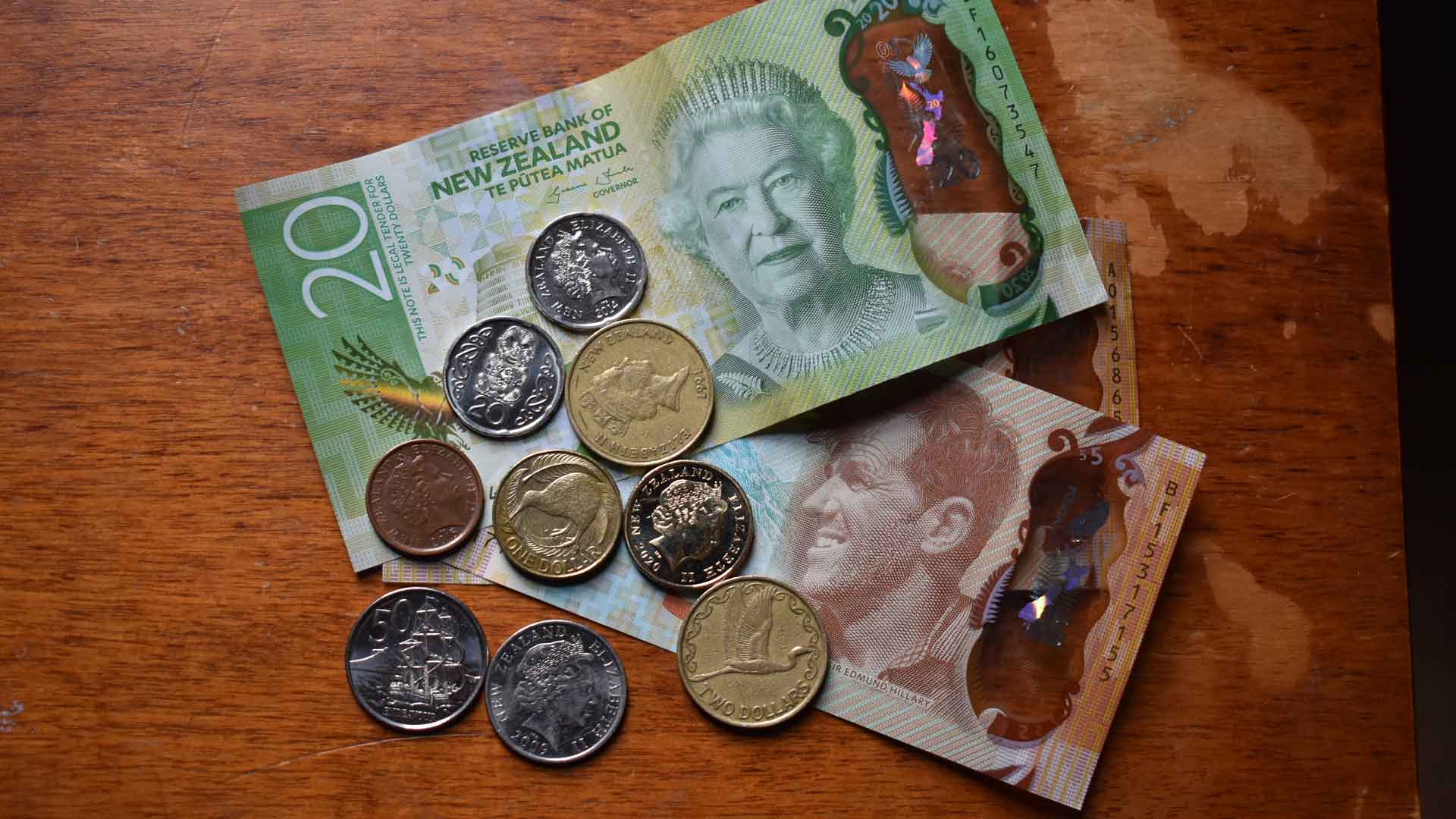Billetes y monedas de Nueva Zelanda organizados sobre una mesa