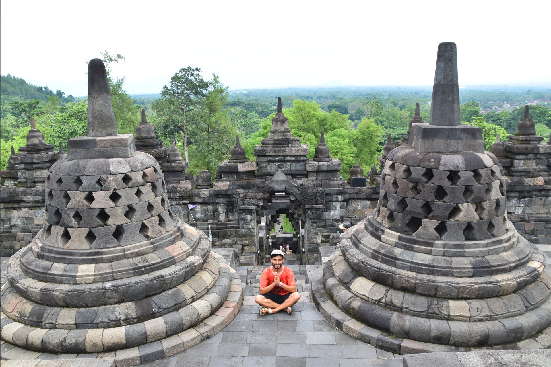 Hombre en posición de gratitud frente a templo Borobudur en Indonesia.