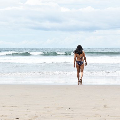 Camila caminando hacia la playa de aguas turquesas en Indonesia.