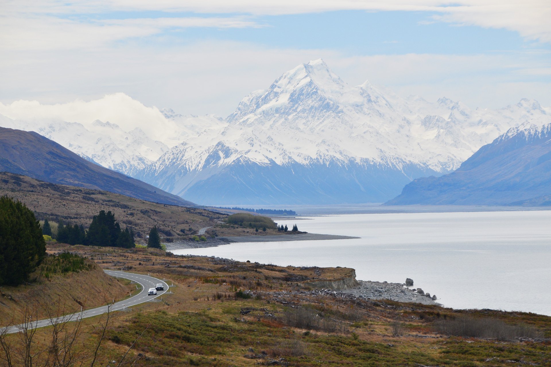 Carretera solitaria, lago azul y Mount Cook en el horizonte.