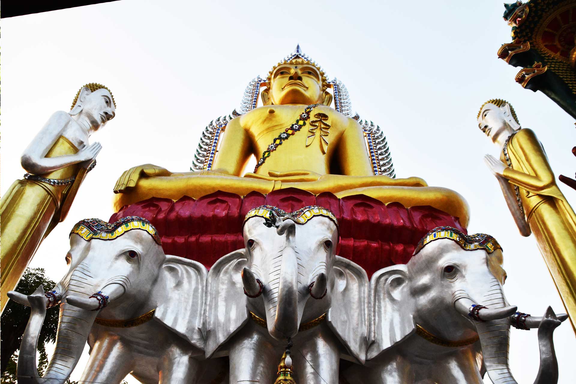 Buda dorado gigante con estatuas de elefantes y guerreros protectores en templo de Bangkok.