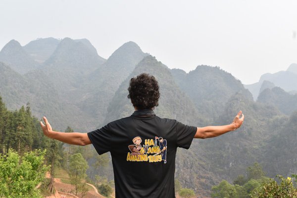 John con camiseta de Ha Giang Tour y montañas de fondo en Vietnam.
